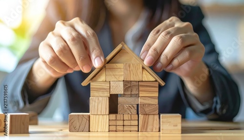 Hands building small wooden block house model.