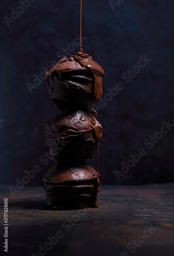Liquid chocolate dripping on stack of three chocolate muffins