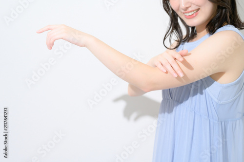 白背景で腕に日焼け止めを塗る日本人女性のビューティイメージ