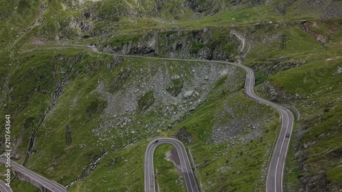 Forward drone flight above the winding Transfăgărășan road as cars travel uphill and downhill through the spectacular Făgăraș Mountains.