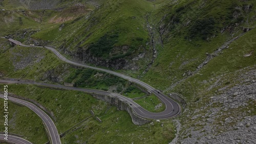 Static aerial footage capturing motorcyclists climbing famous hairpin bends while cars travel through the spectacular Transfăgărășan mountain pass.