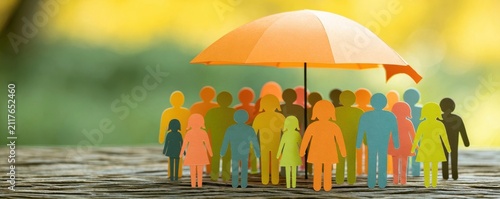 Group of colorful paper figures standing together under a large orange umbrella