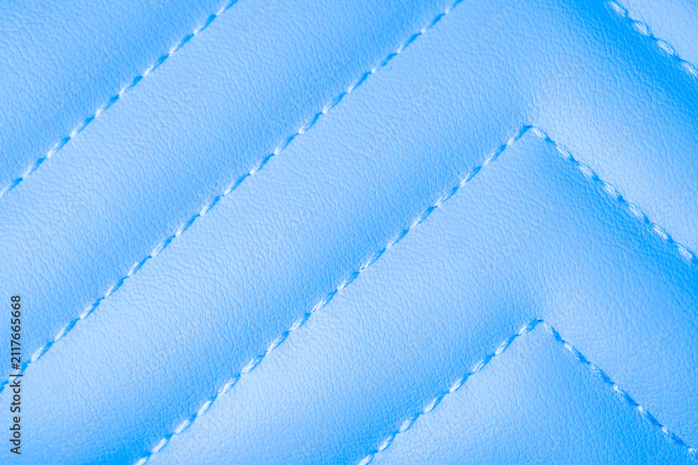 Obraz premium Smooth light blue quilted leather material background with elegant white diagonal stitching detail