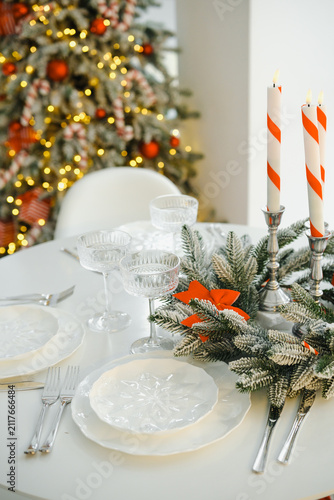 Foto Festive table setting with glowing Christmas tree and candlelit dinner plates an