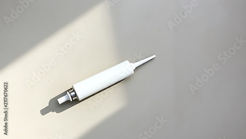 White caulk tube and applicator gun with sealant bead on concrete, home sealing and renovation concept