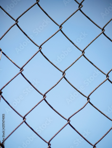 Canvastavla A metallic chain link mesh fence stands against a clear blue sky background