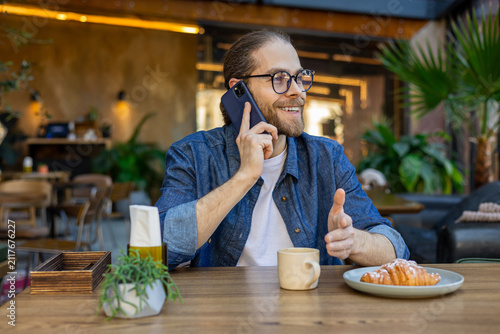 фотографія Caucasian man with a phone in hands in a cafe
