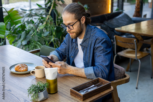 Foto Caucasian man with a phone in hands in a cafe
