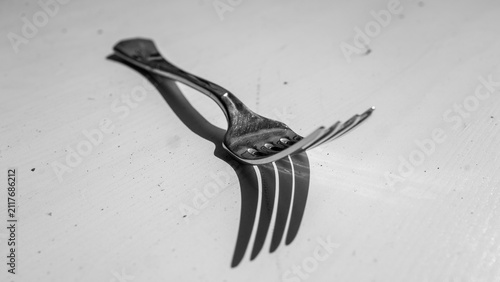 Fotografie Close-up black pitchfork garden tool with curved metal tines on light concrete b