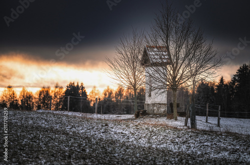 Foto Small historical wayside shrine on a snowy field during dramatic winter sunset