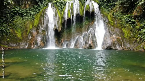 Lush tropical waterfall flowing into a clear green lagoon