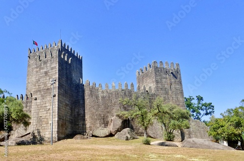 Foto Guimarães Castle with the Portuguese flag waving in the wind, one of the Seven Wonders of Portugal