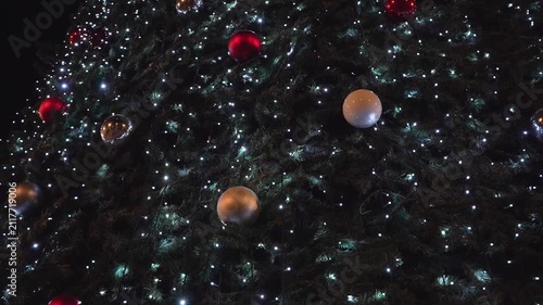Flashing lights and ornaments decorating christmas tree at night
