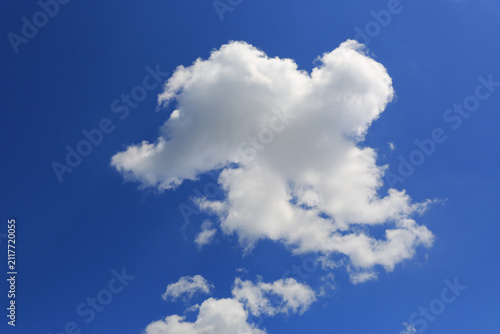 Bild auf Leinwand Fluffy white cumulus clouds drift across a vibrant blue sky on a sunny day