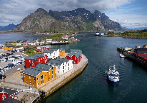 Photography Colorful houses hug the fjord, boats glide on calm waters, and towering peaks ri