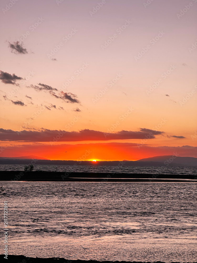 Obraz premium Vibrant sunset illuminating tranquil lake water and distant mountains