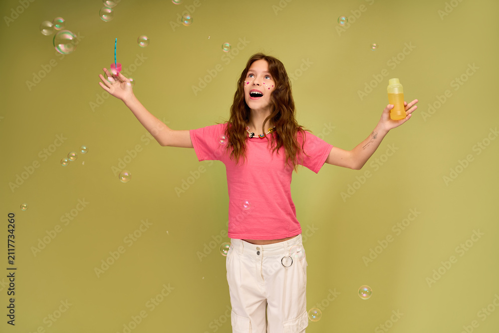 Fototapeta premium Joyful little girl surrounded by bubbles, celebrating carefree moments in stylish attire