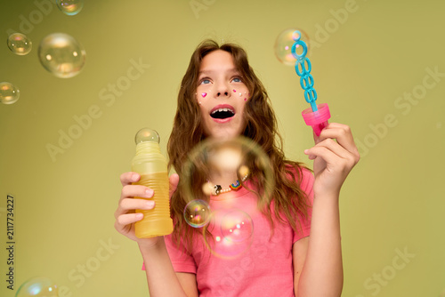 Joyful girl blowing bubbles on a sunny day in her playful, colorful outfit
