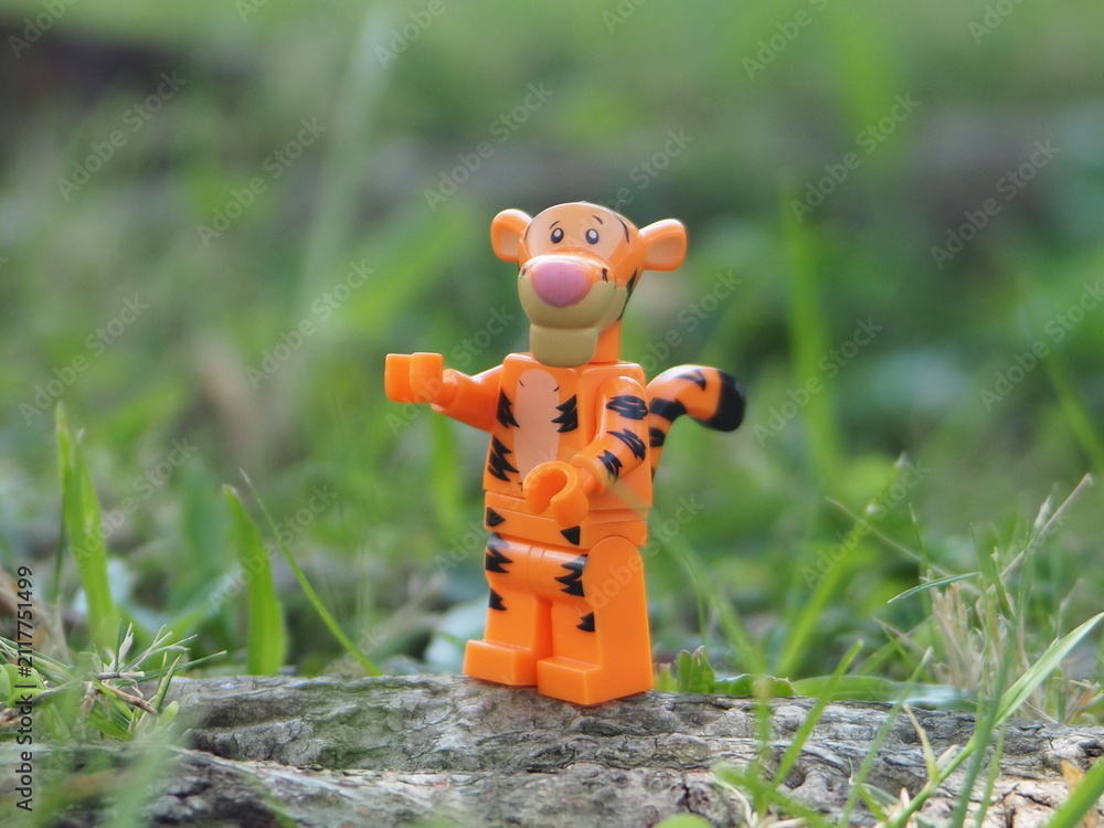 Naklejka premium Indonesia - May 7, 2025 : Mini toy of action figure at outdoor with blurred background. Miniature photography concept design. Minifigure of Tiger character at wild nature.