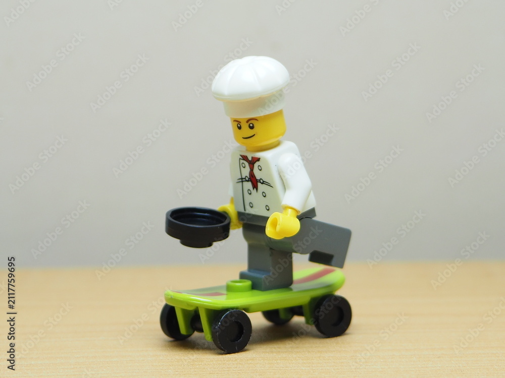 Fototapeta premium Indonesia - February 10, 2026 : Mini toy of action figure at outdoor with blur background. Miniature photography concept design. Minifigure of chef character playing skate board at sport arena.