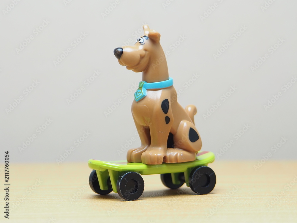Naklejka premium Indonesia - February 10, 2026 : Mini toy of action figure at outdoor with blur background. Miniature photography concept design. Minifigure of Scooby character playing skate board at sport arena.