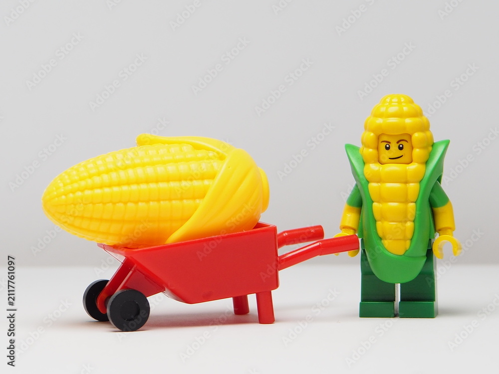 Fototapeta premium Indonesia - February 8, 2026 : Mini toy of action figure at outdoor with blur background. Miniature photography concept design. Minifigure of corn guy character with wheelbarrow at farm land.