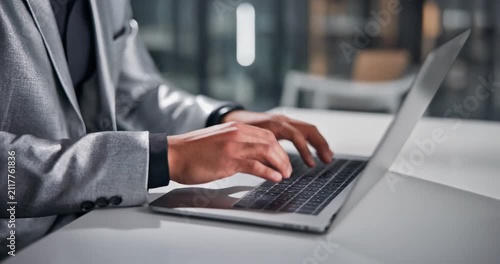 Business professional typing on a laptop computer in modern office setting