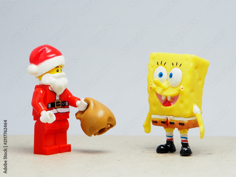Obraz premium Indonesia - November 23, 2025 : Mini toy of action figure at table with blurred background. Miniature photography concept design. Minifigure of Spongebob and Santa Claus character. Christmas theme.