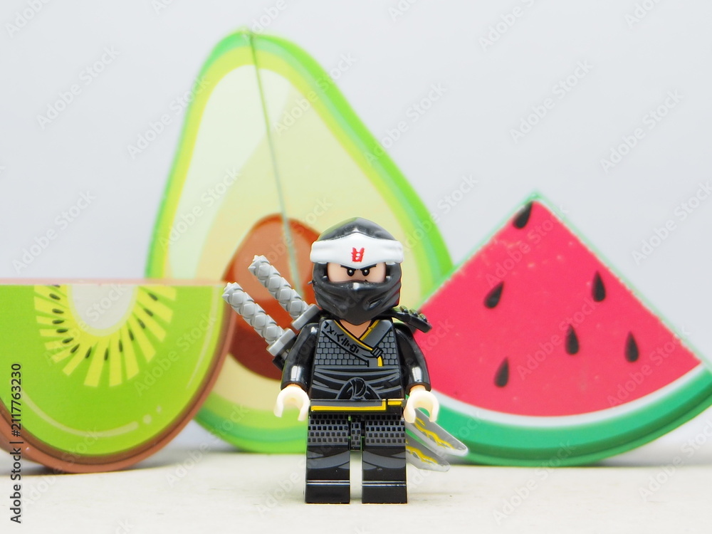 Fototapeta premium Indonesia - December 5, 2025 : Mini toy of action figure at outdoor with blurred background. Miniature photography concept design. Minifigure of Ninja Go character with Avocado, Water Melon and Kiwi.