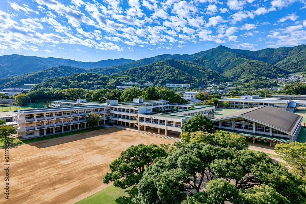 Naklejka premium 青空の下広がる日本の学校グラウンドと校舎全景
