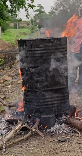 Workers Heating Hot Bitumen in a Metal Drum for Rural Road Construction and Maintenance, vertical and horizontal video
