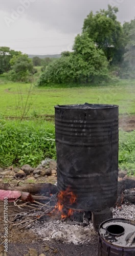 Workers Heating Hot Bitumen in a Metal Drum for Rural Road Construction and Maintenance, vertical and horizontal video