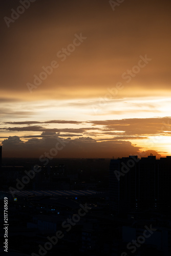 Sunset sky cloud city silhouette horizon dusk orange city skyline under dramatic cloud at dusk with warm light and dark building silhouette