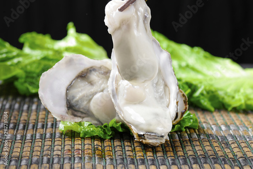 Foto Fresh Raw Oysters on Bamboo Mat with Green Lettuce Studio Food Photography
