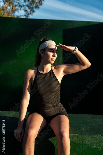Modern athlete shading her eyes in bright evening sun