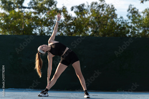 Athletic woman stretching on an urban court