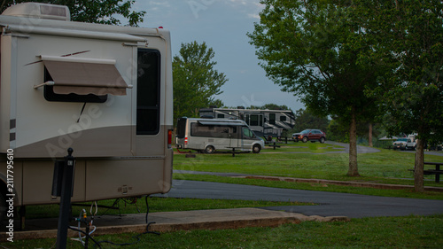 Early morning light at campsite with Rv parked under tall trees with path to sites