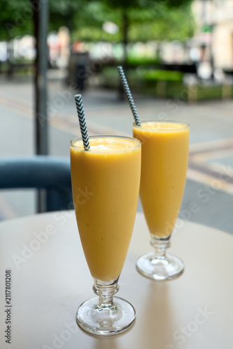 Two tall glasses filled with thick organic yellow fruit smoothie