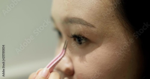 Close-up of young Asian woman putting on false eyelashes