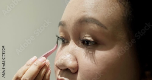 Close-up of young Asian woman putting on false eyelashes
