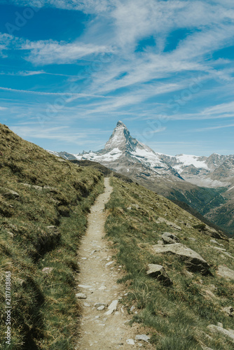 Winding path on a grassy hillside with the iconic matterhorn mountain in the distance