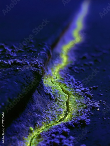 Fluorescent Green-Yellow Magnetic Particles Glow Along a Crack in Dark Metal Under Ultraviolet Light
