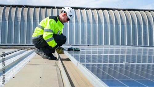 Worker installs solar panels on a rooftop during daylight hours at a commercial building