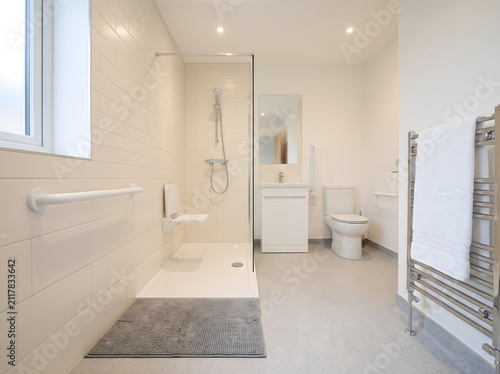 Bright accessible bathroom with grab bar and non-slip mat for elderly safety