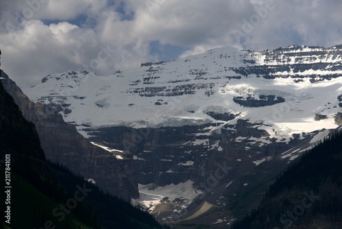 Quadro su tela An intimidating close-up perspective showcases the massive, heavily fractured ice cliffs and layered rock ledges of the legendary Victoria Glacier towering grandly above the shaded Lake Louise valley