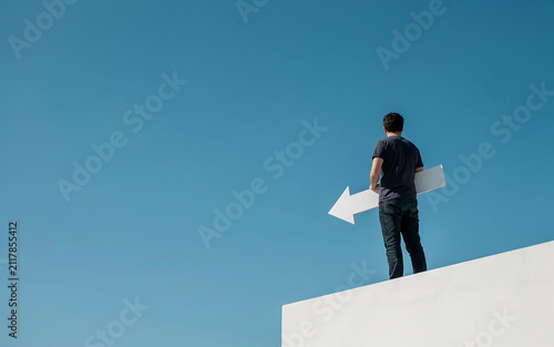 Young professional holding left pointing sign standing on white wall against blue background with direction decision business navigation strategy pointing opportunity standing thinking
