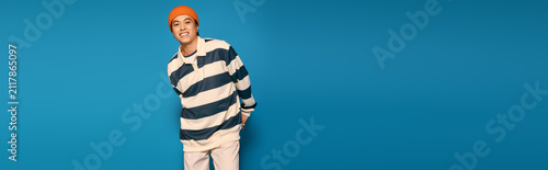 Stylish young man in a striped outfit poses confidently in a vibrant studio setting