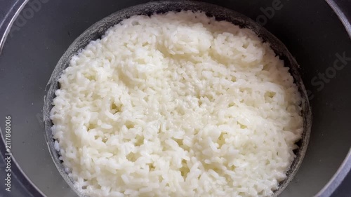 Close-up of freshly cooked white sticky rice inside a metal cooking pot, showing soft moist grains, a staple carbohydrate for Asian meals and domestic home cooking, simple nutritious food preparation.