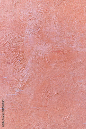 Textured salmon pink plaster wall with circular swirl patterns and rough stucco finish