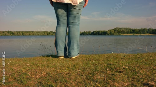 Woman by lake side with summer meadow flowers